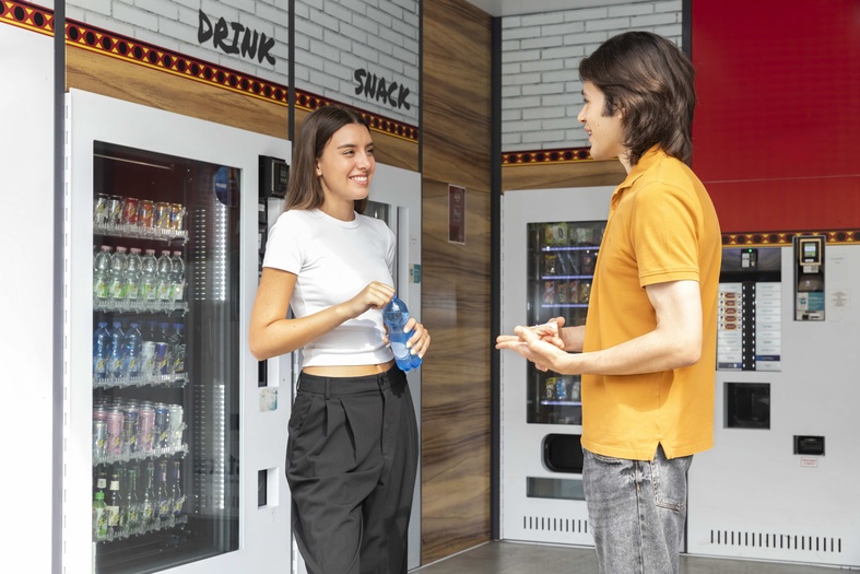 Due ragazzi davanti ai distributori automatici in un negozio H24, simbolo del ruolo dei punti vendita automatici nei servizi di prossimità